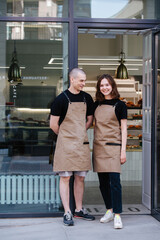 Two coworkers posing in the entrance in the transparent bakery shop front