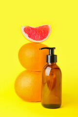 Bottle of essential oil and grapefruits on color background