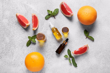 Composition with bottles of essential oil, mint and grapefruit slices on grunge background