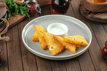 Deep fried cheese triangles with sour cream sauce on a wooden background