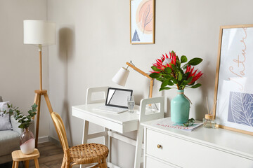 Comfortable workplace with protea flowers in interior of room