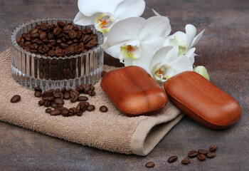 Glasschale mit Kaffeebohnen einer Orchideenblüte und Kaffeeseife. 