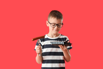 Little boy with tasty sausage on color background