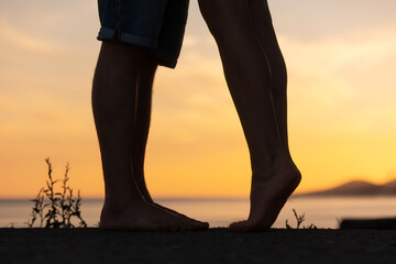 Silhouette of a couple kissing. Legs close-up. Sunset in the background. Valentines day concept