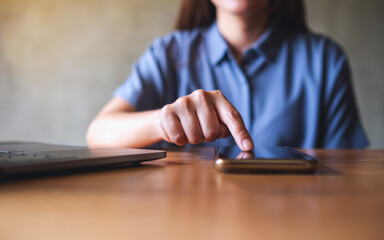 Closeup image of a woman using mobile phone and laptop computer