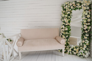 White vintage sofa and large mirror with artificial flowers