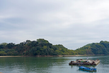 Fototapeta na wymiar 海の浮かぶ筏と船と島