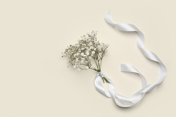 Beautiful gypsophila flowers and ribbon on color background