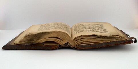 An old book is open lying on a white background