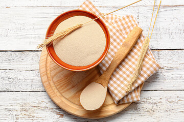 Composition with bowl of active dry yeast on light wooden background