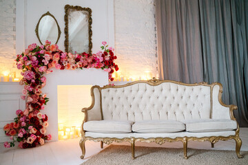 Vintage sofa, chair, table with candles. Fireplace decorated with flowers