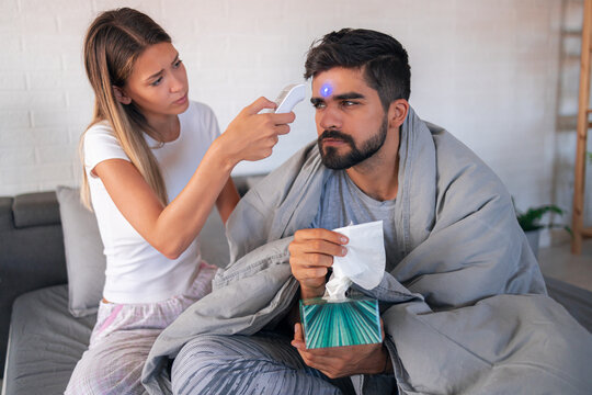 Worried girlfriend measuring her boyfriends' temperature