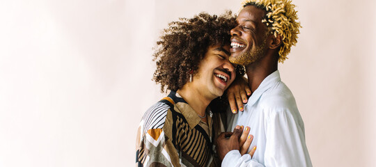 Happy young gay couple standing in a studio - obrazy, fototapety, plakaty