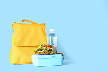 Lunch box bag, bottle of water and sandwich on color background