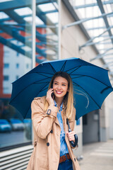 Gorgeous lady having business call under big blue umbrella
