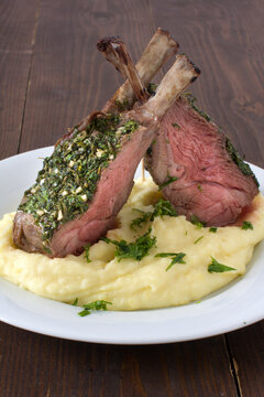 Piece of lamb rack with bone roasted with green herb crust served with potatoe mash