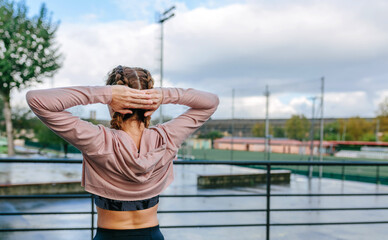 Young sportswoman stretching neck and shoulders outdoors