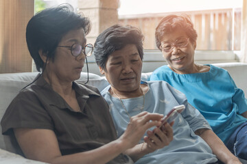 Aging society concept with Asian elderly senior adult women sisters using mobile digital smart phone application technology for social media network among friends community via internet communication