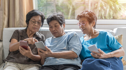 Aging society concept with Asian elderly senior adult women sisters using mobile digital smart...