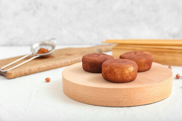 Board with tasty cacao mochi on light background