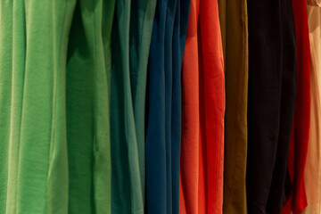 Multicolored cotton T-shirts on a hanger in a store. Close-up.
