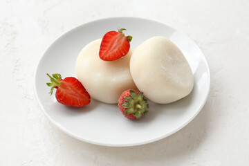Plate with tasty Japanese mochi and strawberry on light background