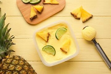 Container with tasty pineapple ice cream on color wooden background