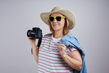 woman tourist in a hat uses a camera, takes a picture. Isolate on gray background