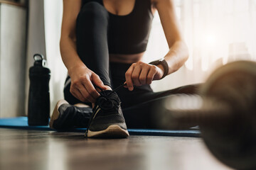woman tying shoes.A person running in tracksuit tying her shoelaces in gym