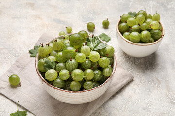 Bowls with fresh ripe gooseberry on grunge background