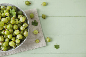 Bowl with fresh ripe gooseberry on color wooden background