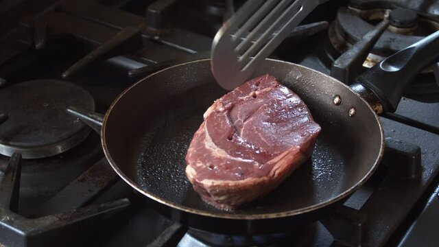 High angle view of cooking a Rump steak, seasoning it, and flipping it over.