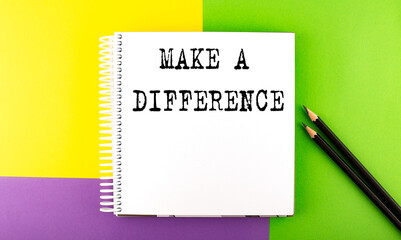 Minimal work space : sketchbook on the colorful background with MAKE A DIFFERENCE text