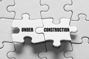 Fototapeta premium Under construction message on connected jigsaw puzzle pieces. Site construction or maintenance