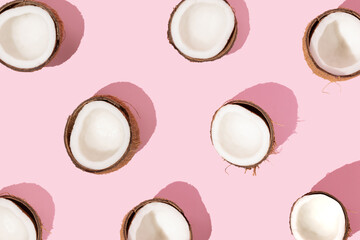 Pattern with ripe coconuts on pink background. Creative summer concept.  Half of coconut in minimal...