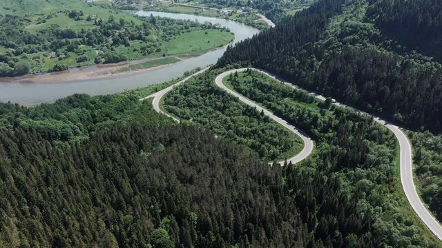 Flight over the summer mountains with mountain road serpentine