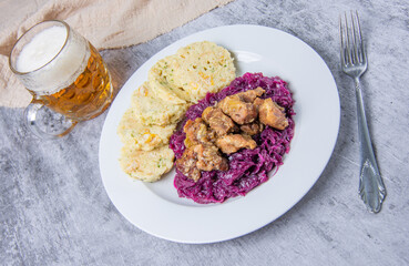 Roast pork with dumplings and sauerkraut. Typical Czech national dish with homemade bread dumplings red cabbage and beer on stone background.