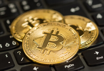 Three bitcoin gold coins placed on a keyboard of laptop