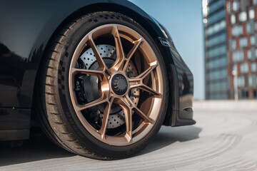 The front wheel of sport car. Expensive and luxury supercar golden rims at the empty parking lot