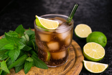 Cuba Libre cocktail with lime and brown rum on a wooden board.