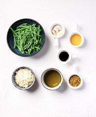 Ingredients for cooking green beans: balsamic vinegar, honey, mustard, almonds, olive oil standing on a white table. Top view
