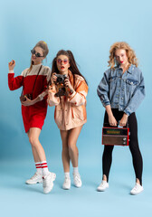 Pretty young women in retro 90s fashion style, outfits posing isolated over blue studio background....