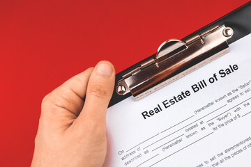 Man hold real estate bill of sale form. Mortgage concept. Red background photo