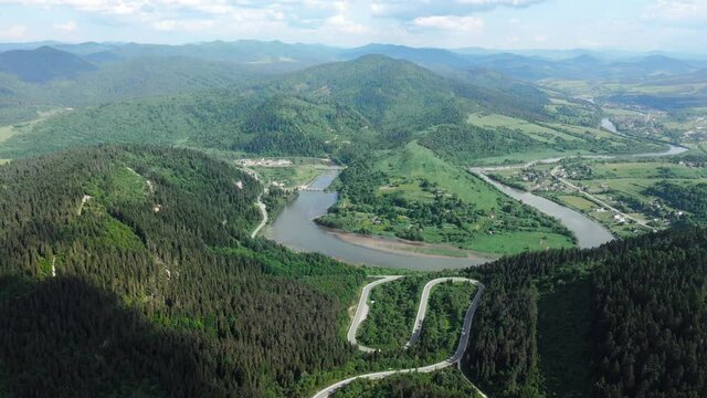 Flight over the summer mountains with mountain road serpentine