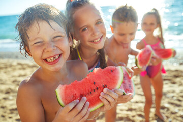 Children with a watermelon at the sea. A group of children have fun playing at the sea. High quality photo - 446590782