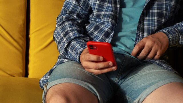 a man using a red phone while sitting on the couch