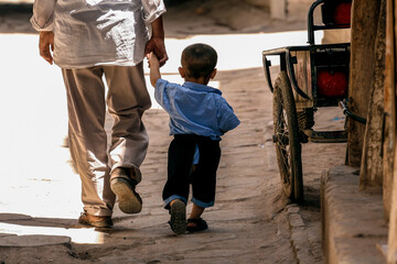 Uighur man holding hands with his son in a street in Kashgar, Xinjiang, China