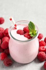 Yummy raspberry smoothie in jar and fresh berries on table