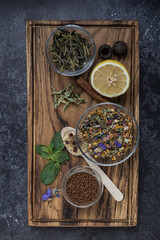 Rectangular wooden board with various types of tea, herbs and spices