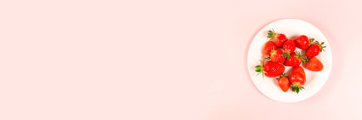 Top view strawberry on white plate on a pink background. horizontal space for text